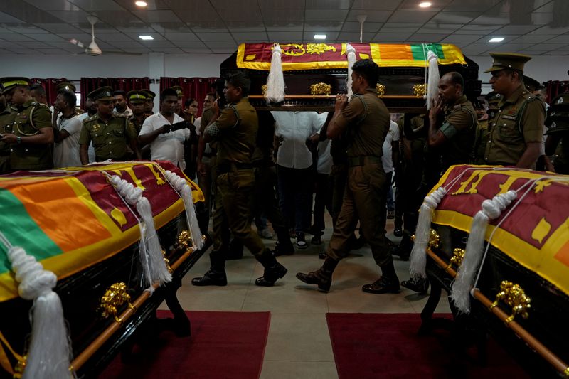 Members of Sri Lanka Prisons Emergency Action and Tactical Force react next to the bodies of prison officials, in Colombo